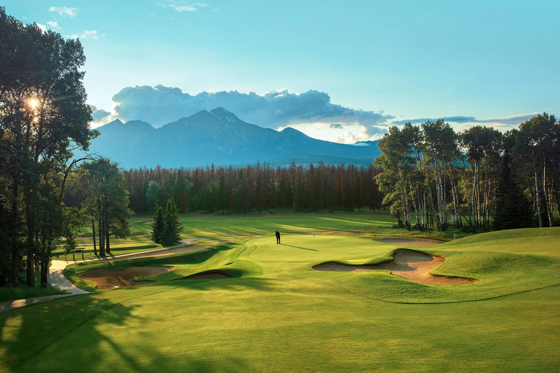 Overhead view of a golfer on a smooth green putting surrounded by sand bunkers