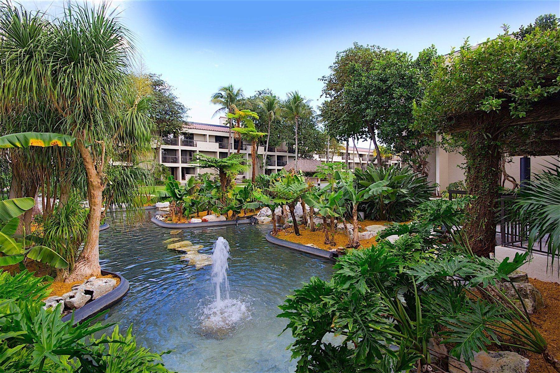 Pond surrounded by trees with a hotel in the background
