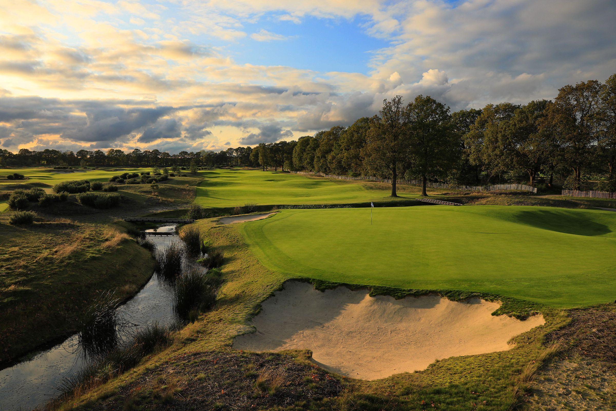 A smooth green surrounded by a water feature with a sand bunker next to it