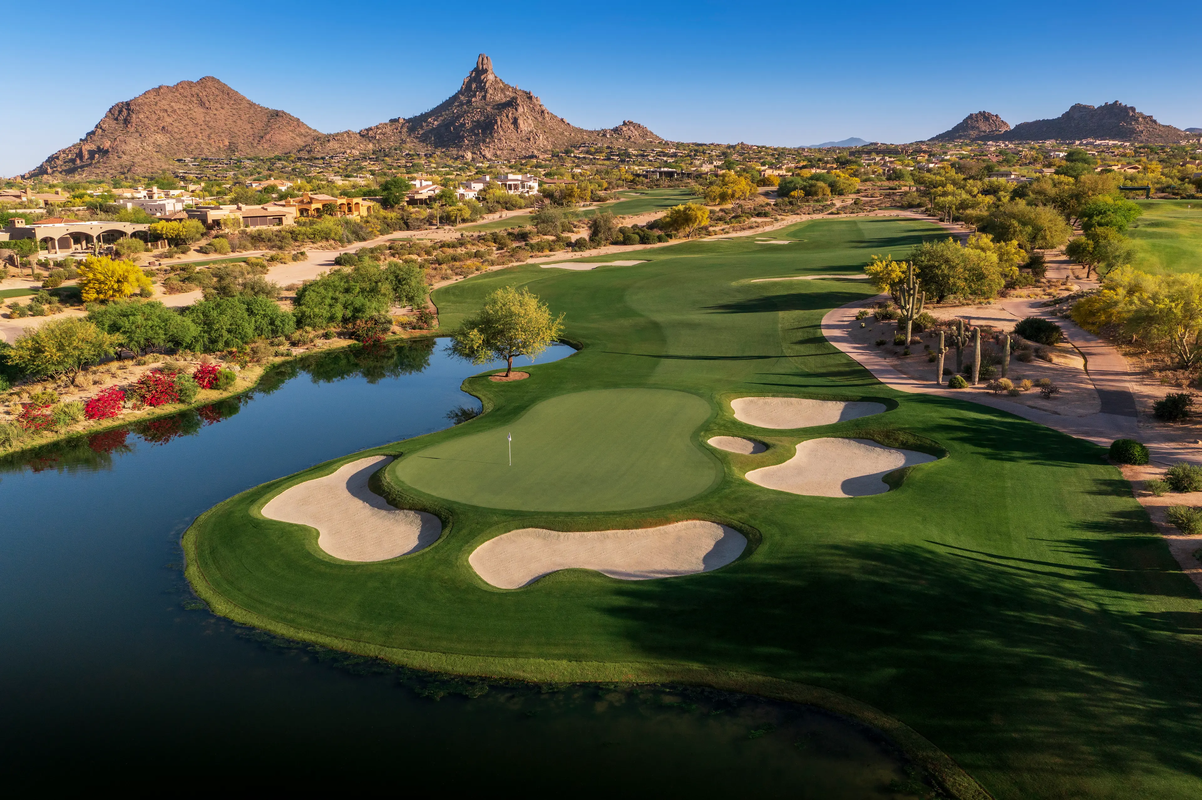 Overhead view of a smooth green surrounded by sand bunker with mountain views in the distance