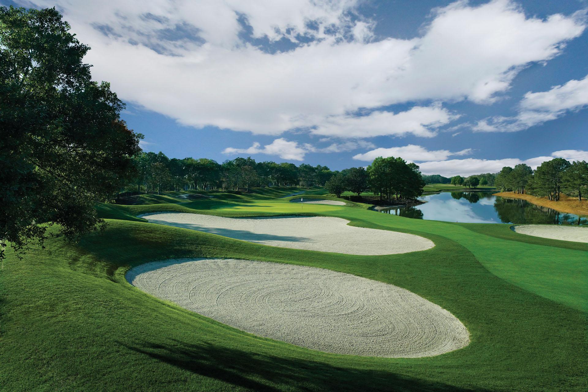 Winding, tree-lined fairway with a large water hazard on one side