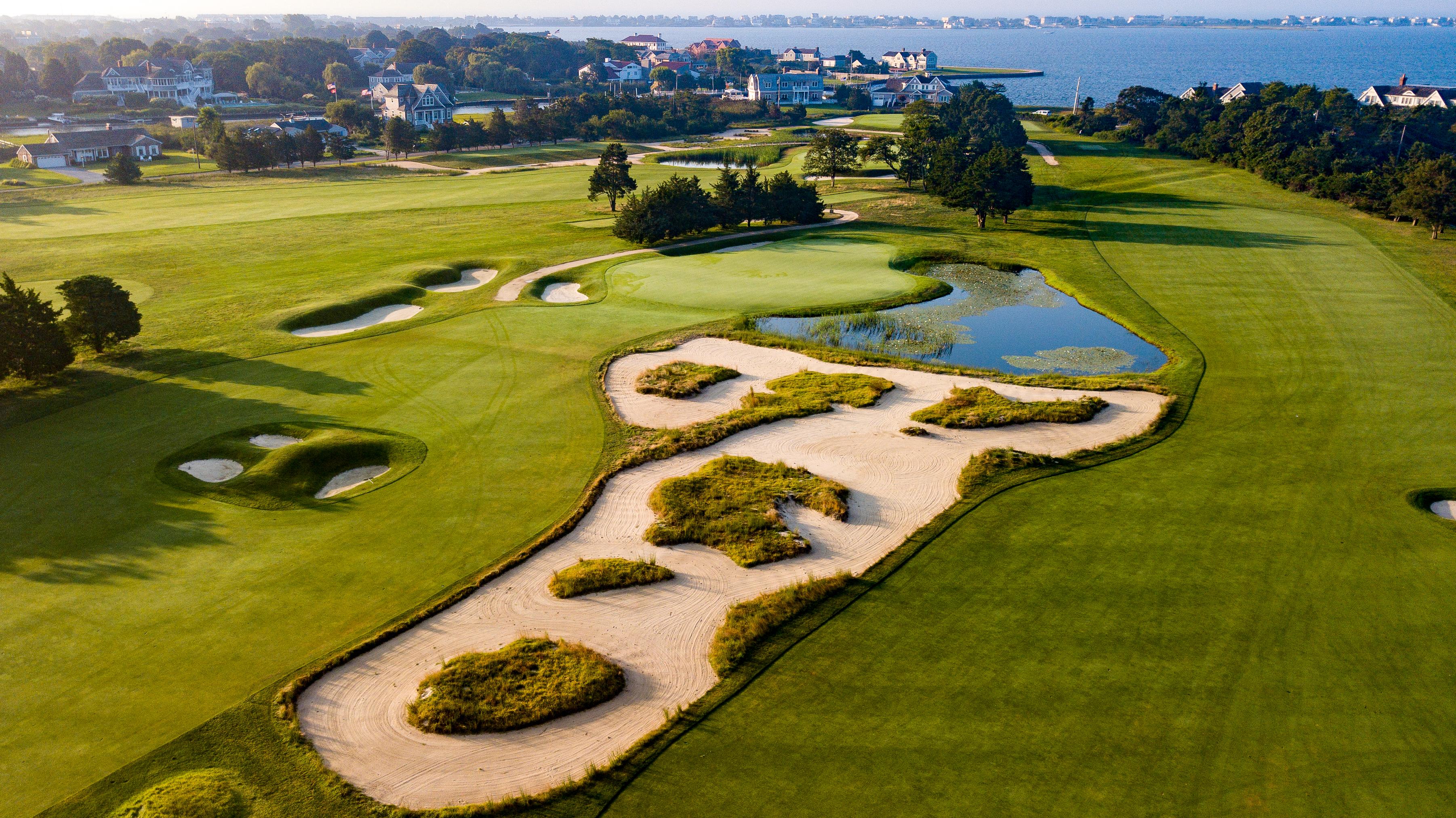 Overhead view of manicured fairways running parallel with a large sand bunker in the centre