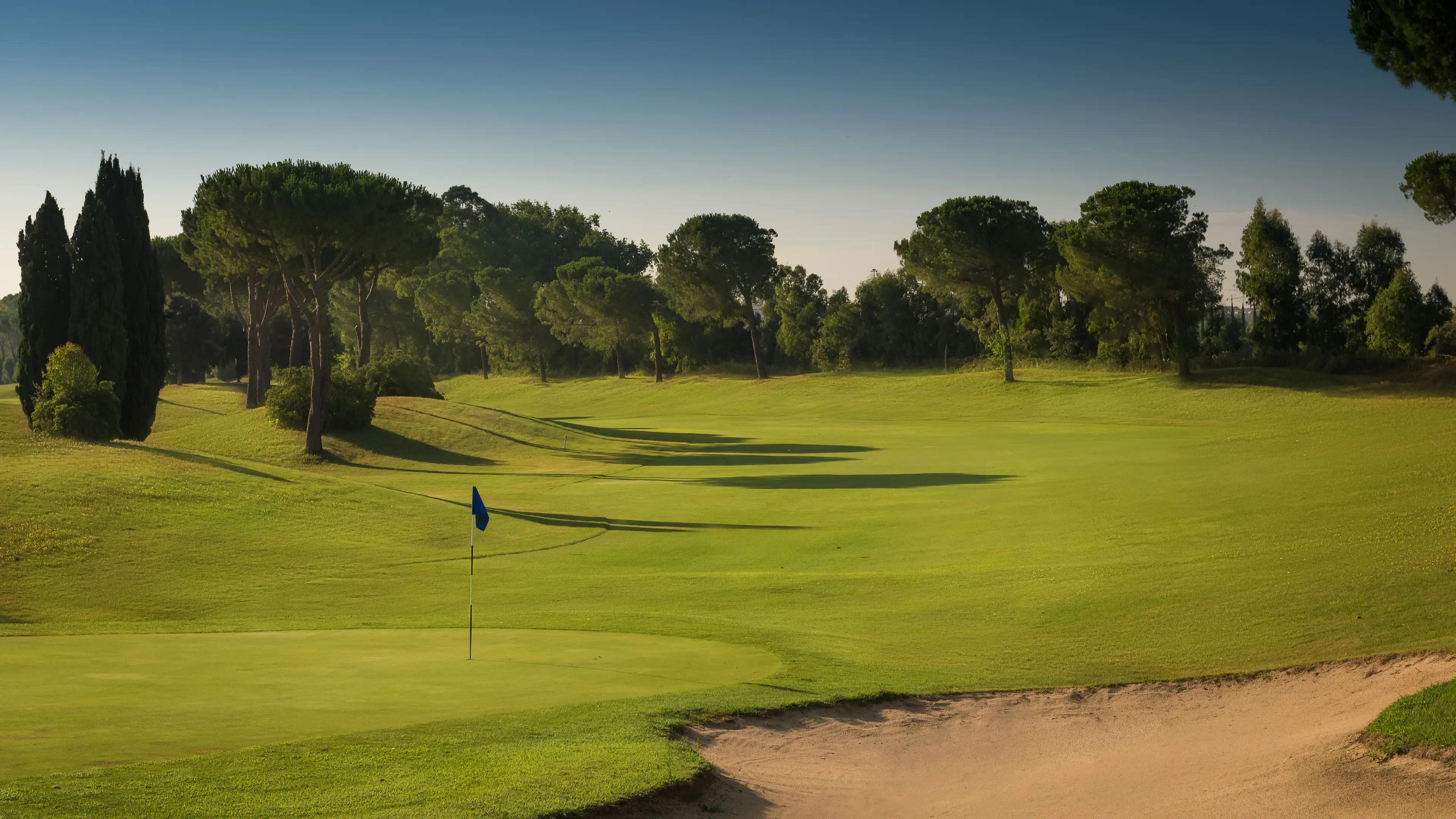 A well maintained fairway leading to a smooth green next to a sand bunker