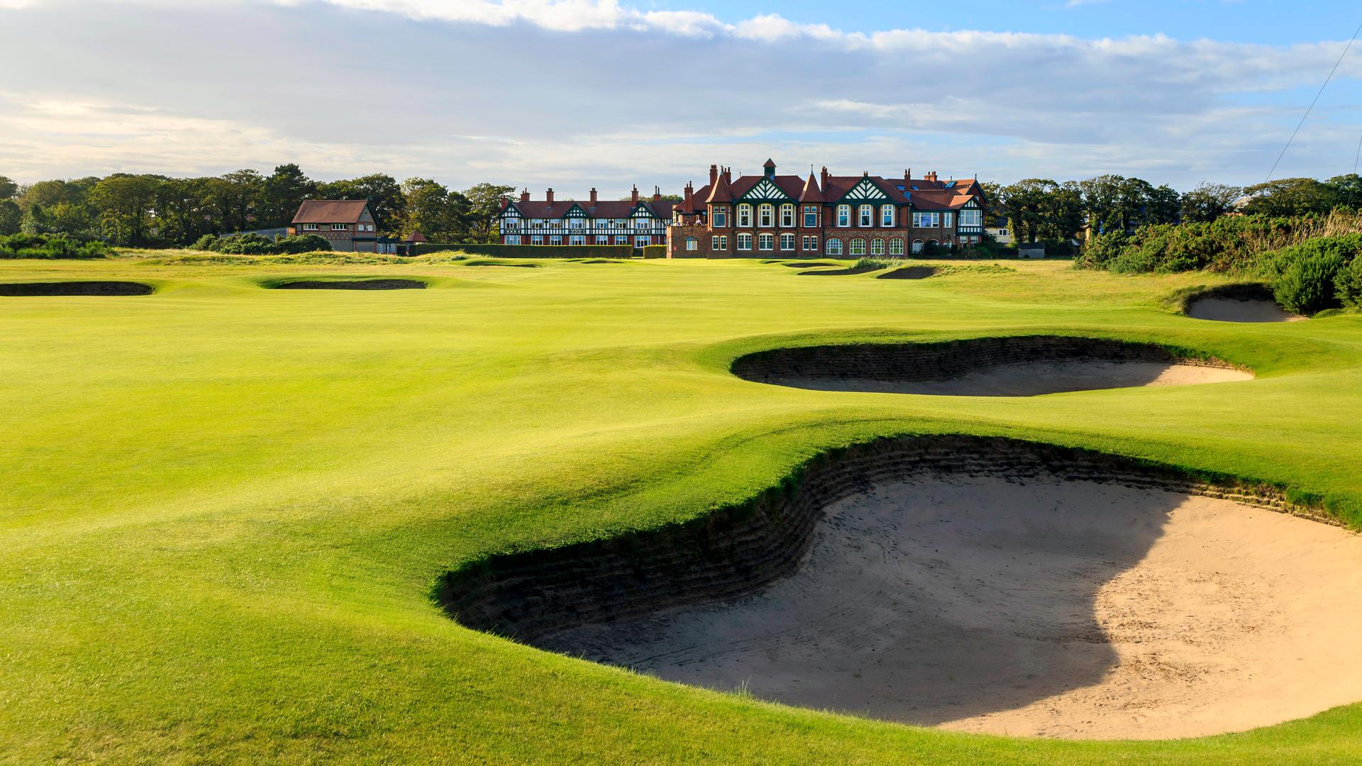 A well maintained fairway nestled with sand bunkers leading t the clubhouse