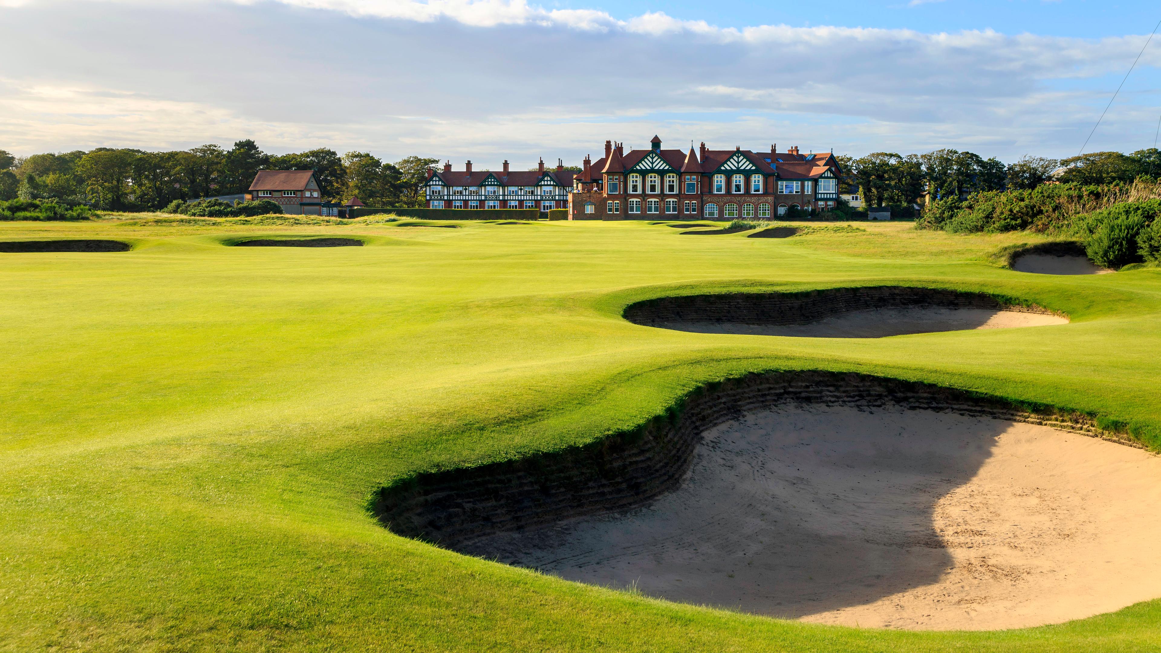 A well maintained fairway nestled with sand bunkers leading t the clubhouse