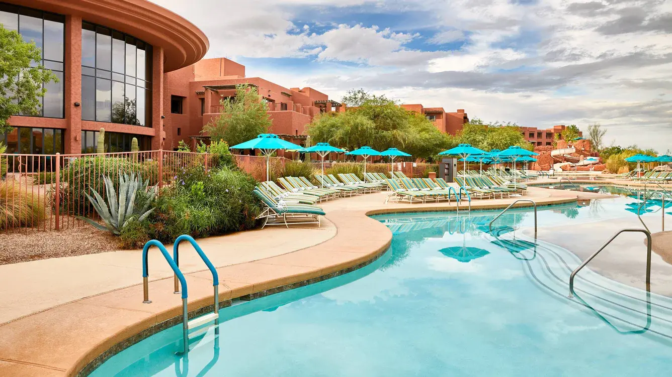 Panoramic view of the outdoor swimming pool surrounded by sunbeds and umbrellas