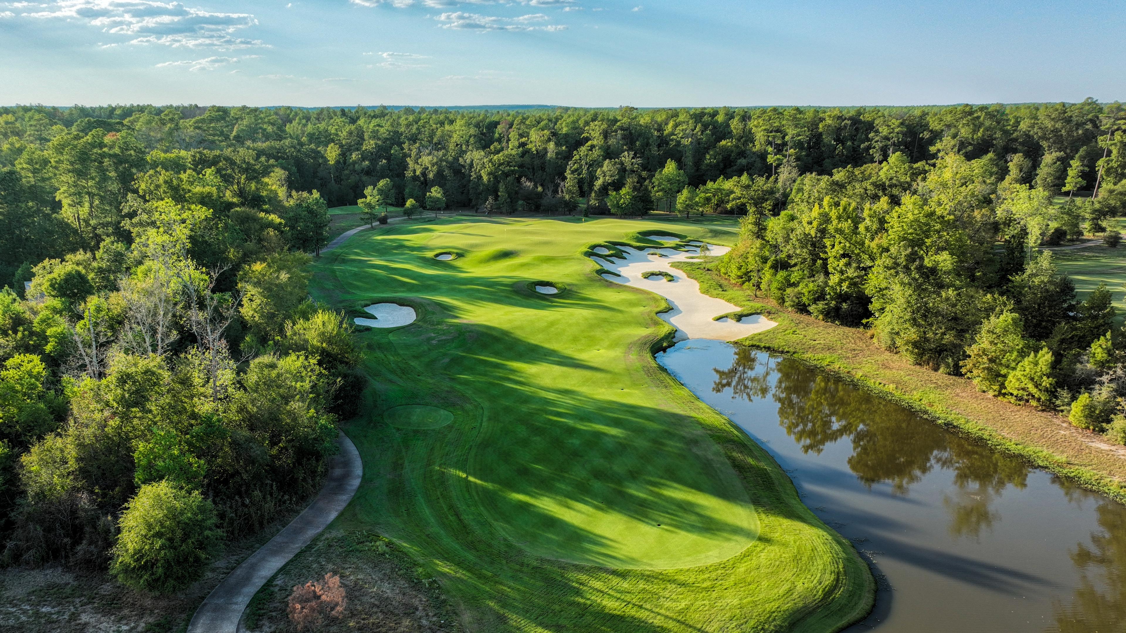 Panoramic view of a manicured fairway nestled with sand bunkers running along a water hazard