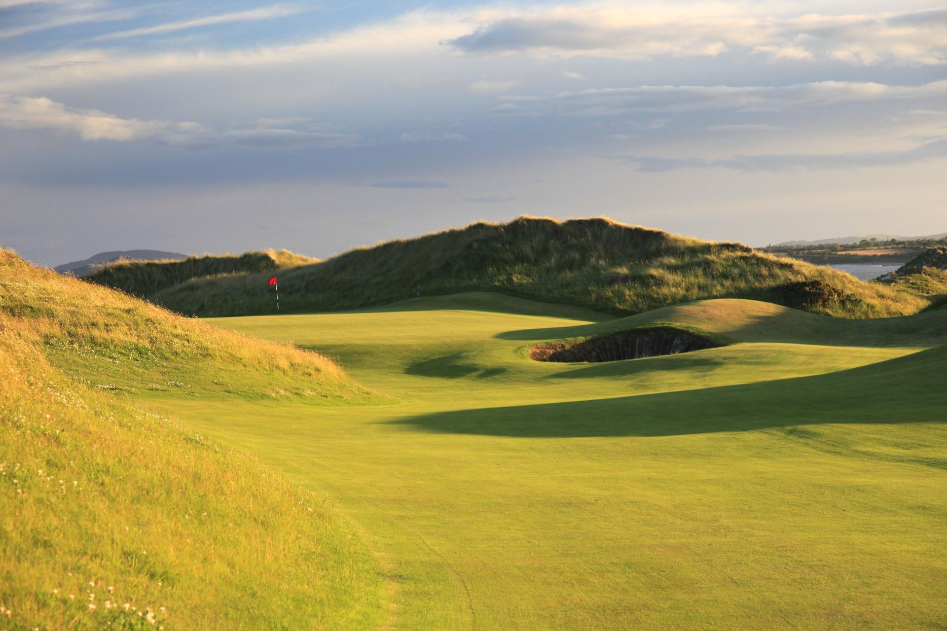 A winding fairway with a deep sand bunker leading to a smooth green