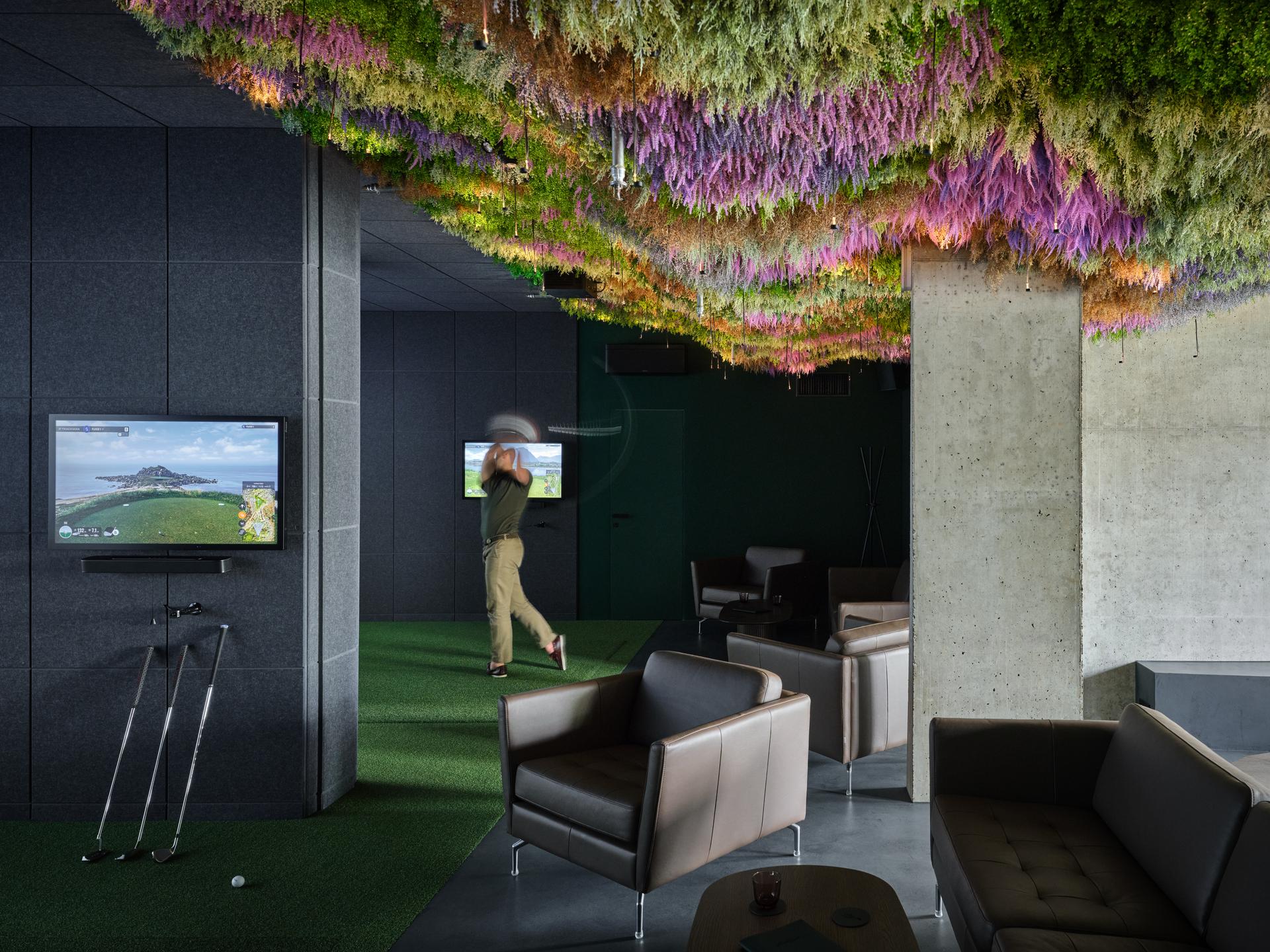 Golfer swinging in a golf simulation at the Albatross Golf Resort