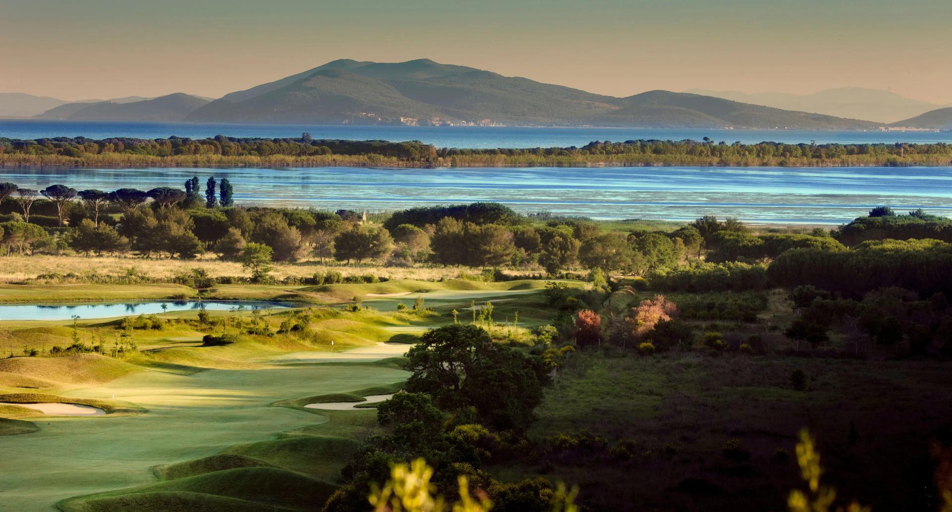 A fairway leadinng towards the water with mountains in the back