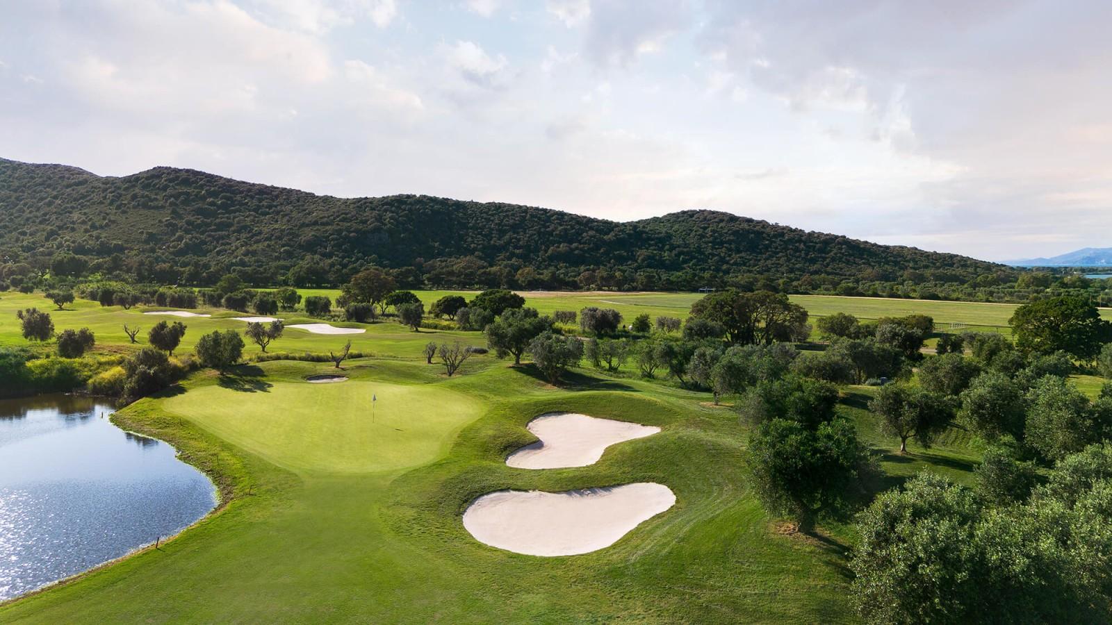 A smooth green sandwiched by sand bunkers and a large water hazard