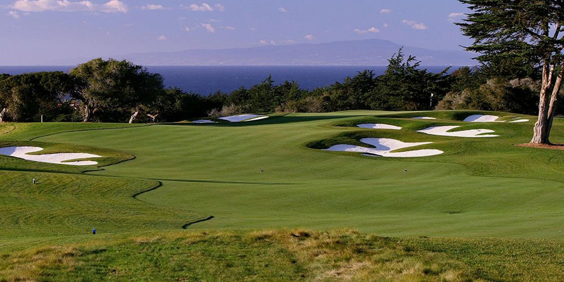 Panoramic view of a winding fairway nestled with sand bunkers with sea views