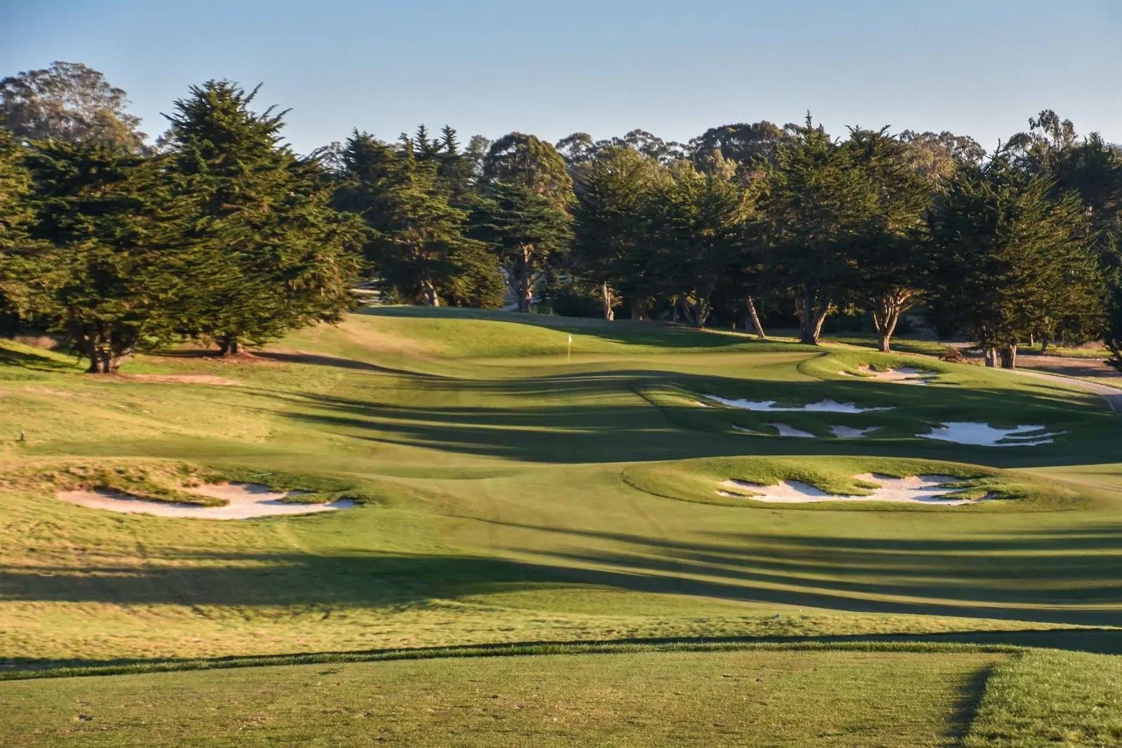 An uphill fairway nestled with sand bunker leading to a smooth green