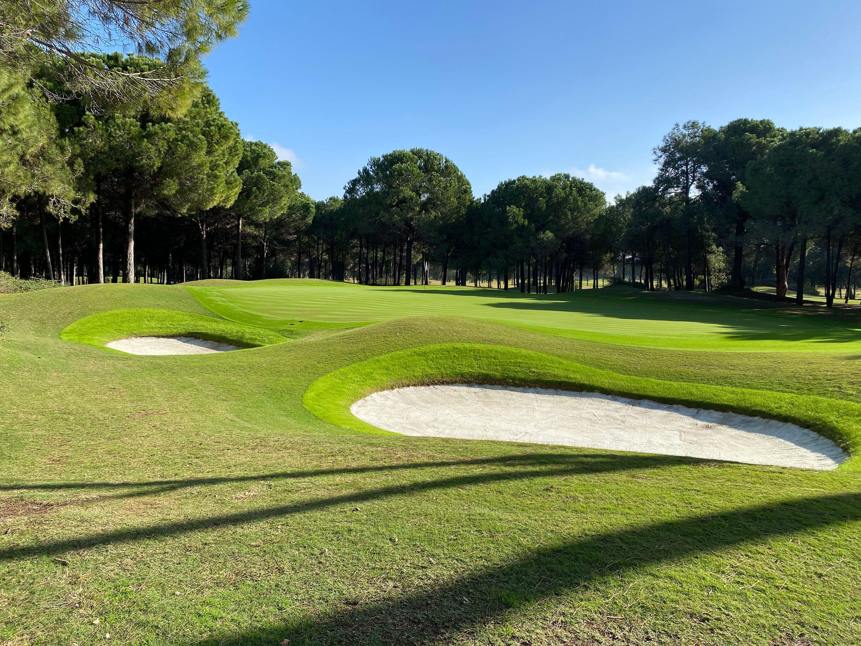 Panoramic view of a smooth green surrounded by sand bunkers at The Pasha Course