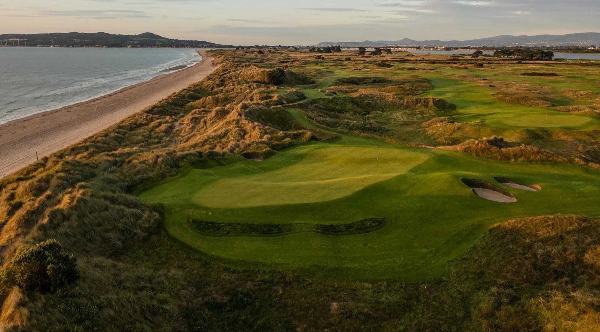 Overhead view of a smooth green with a mature rough dividing it from the coast