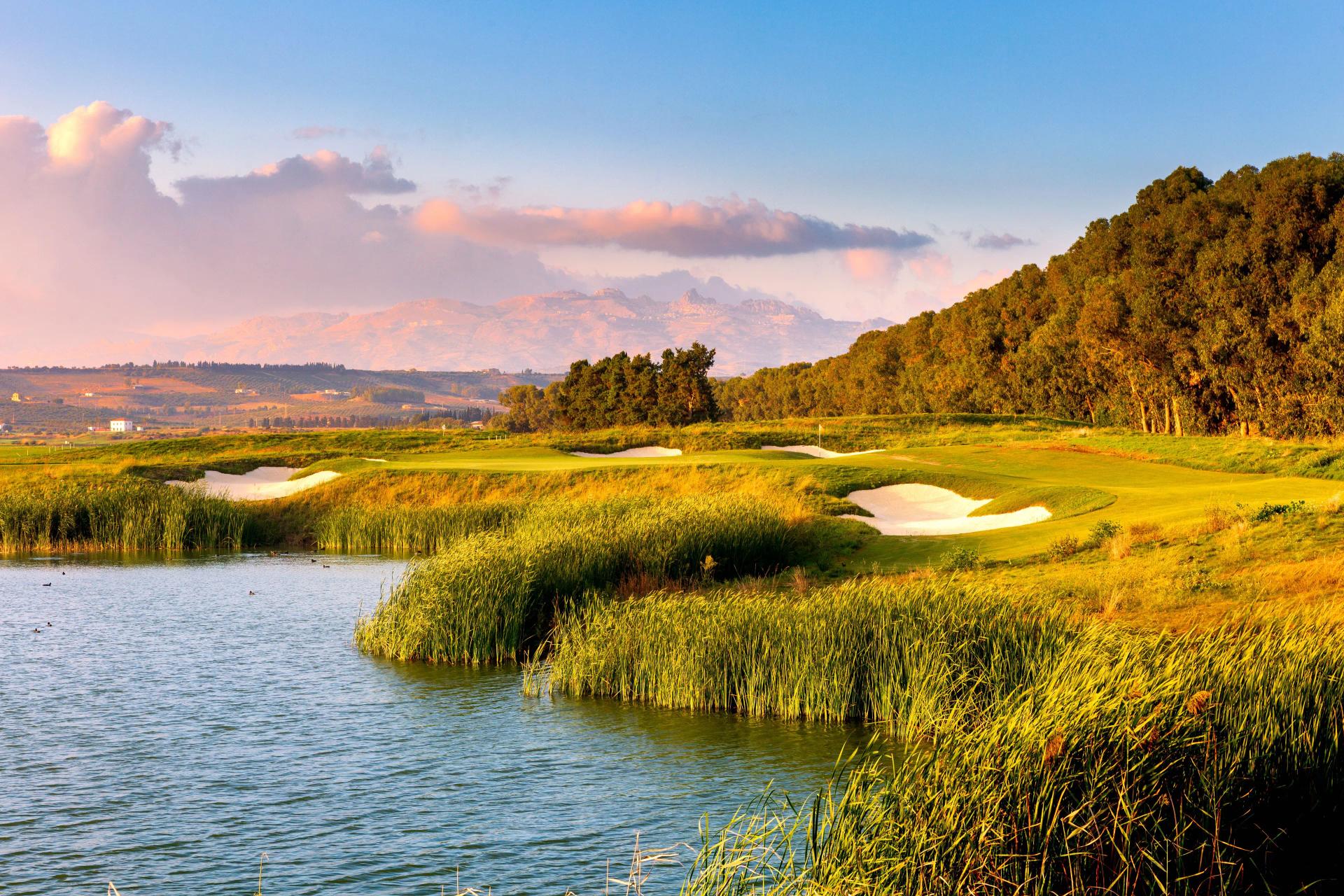 A winding fairway nestled with sand bunkers next to a water hazard