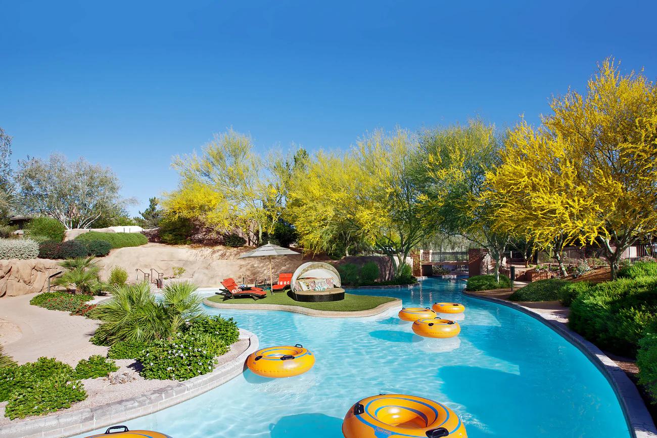 A lazy river at the resort with floaties in the water and sunbeds on an island