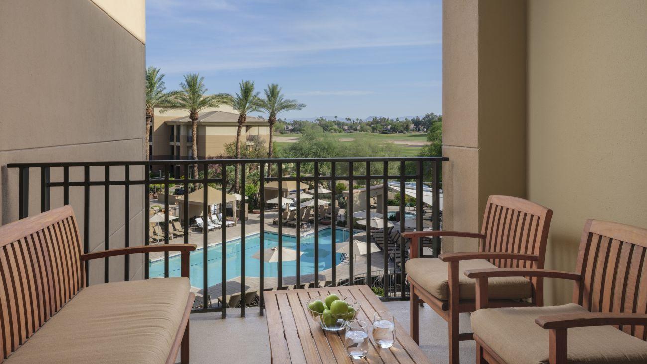 A balcony with views of the outdoor swimming pool and distant views of the golf course