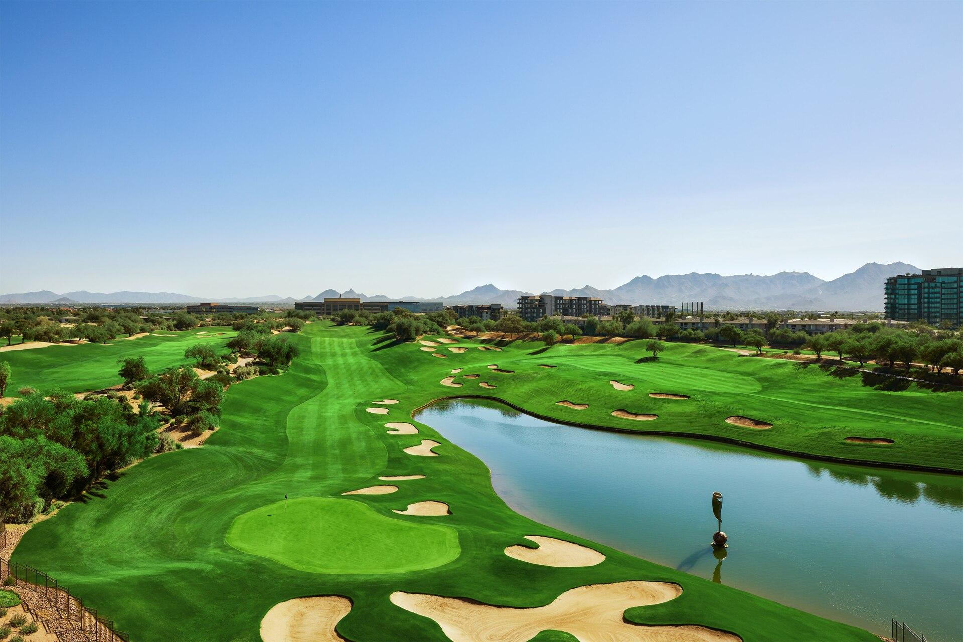 Overhead view of a well maintained fairway littered with sand bunkers next to a water hazard
