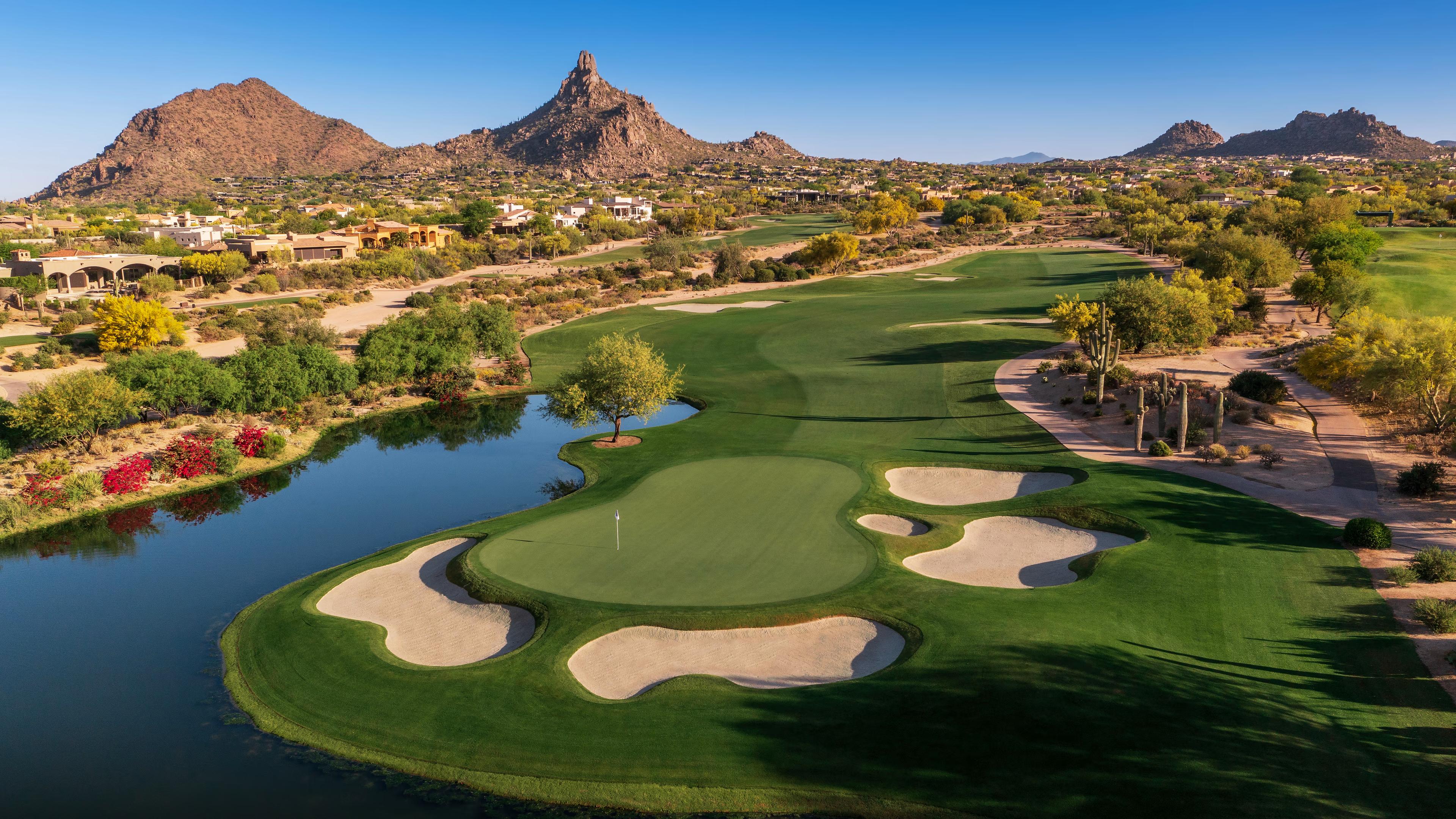 Overhead view of a well maintained green surrounded by sand bunkers next to a water hazard