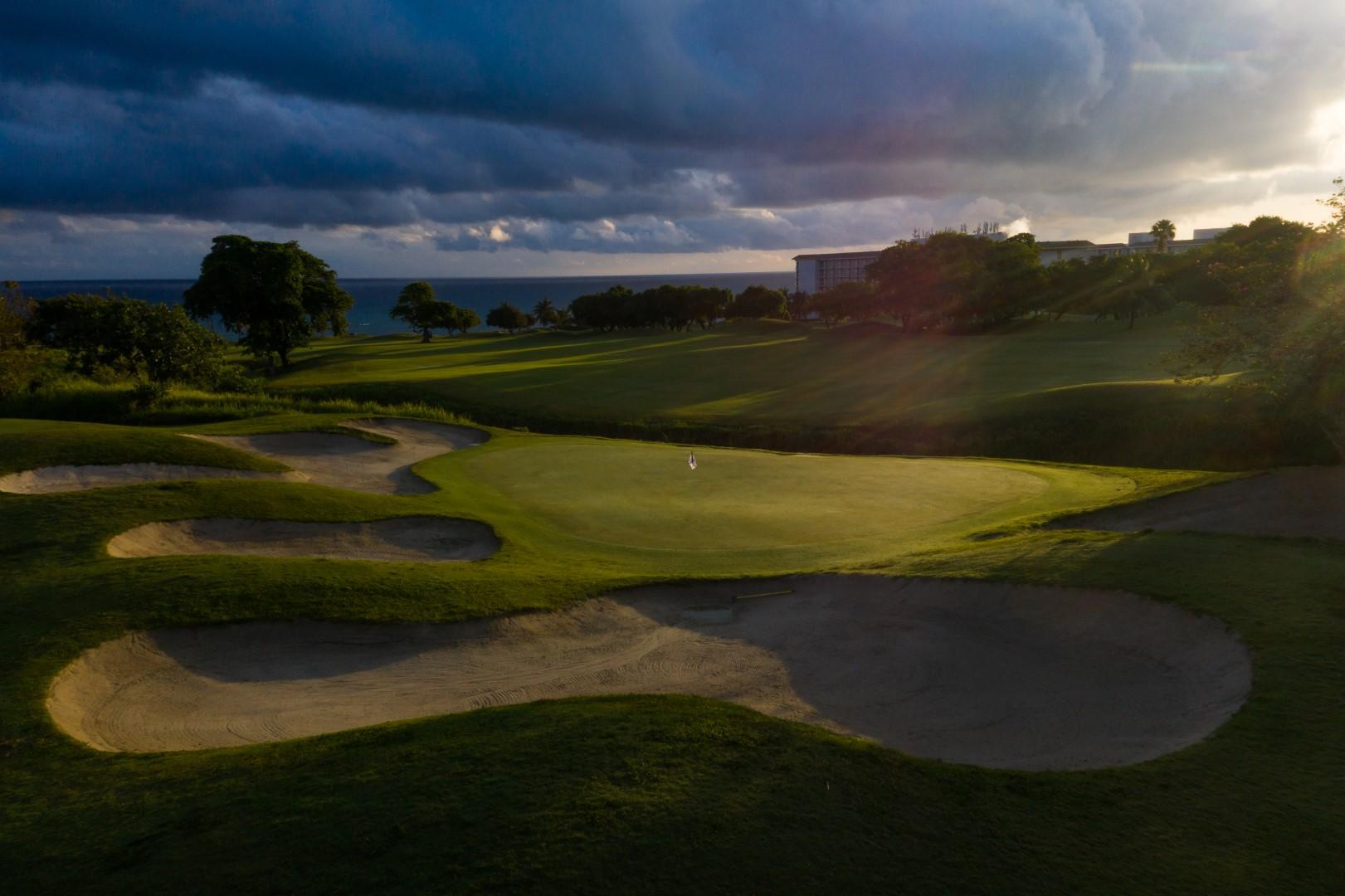 A smooth green surrounded by a large sand bunker