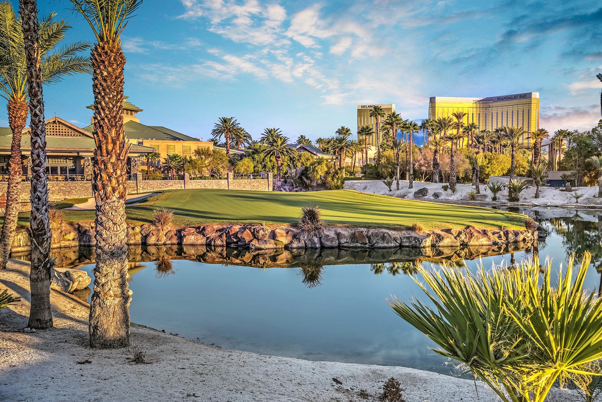 The Bali Hai clubhouse overlooking a water hazard on the course which is reflecting the sun surrounded by palm trees on the rough