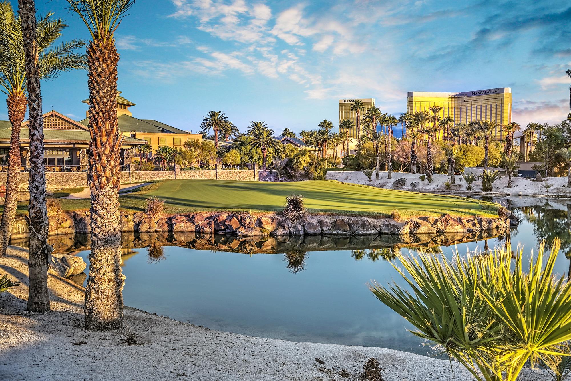 The Bali Hai clubhouse overlooking a water hazard on the course which is reflecting the sun surrounded by palm trees on the rough