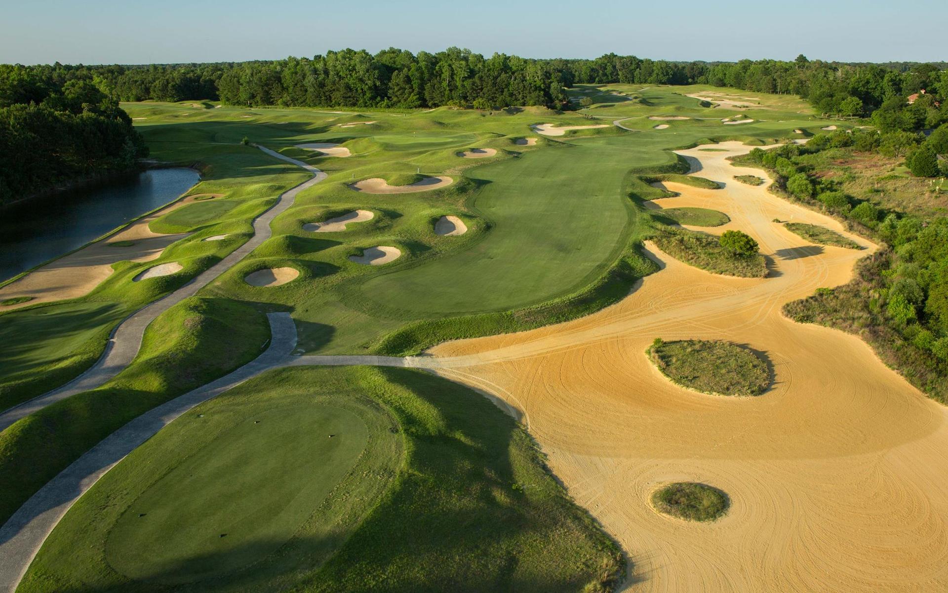Wide fairway being sandwiched by sand bunkers under clear skies