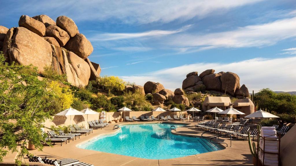 Panoramic view of a swimming pool surrounded by checkered sunbeds under blue skies