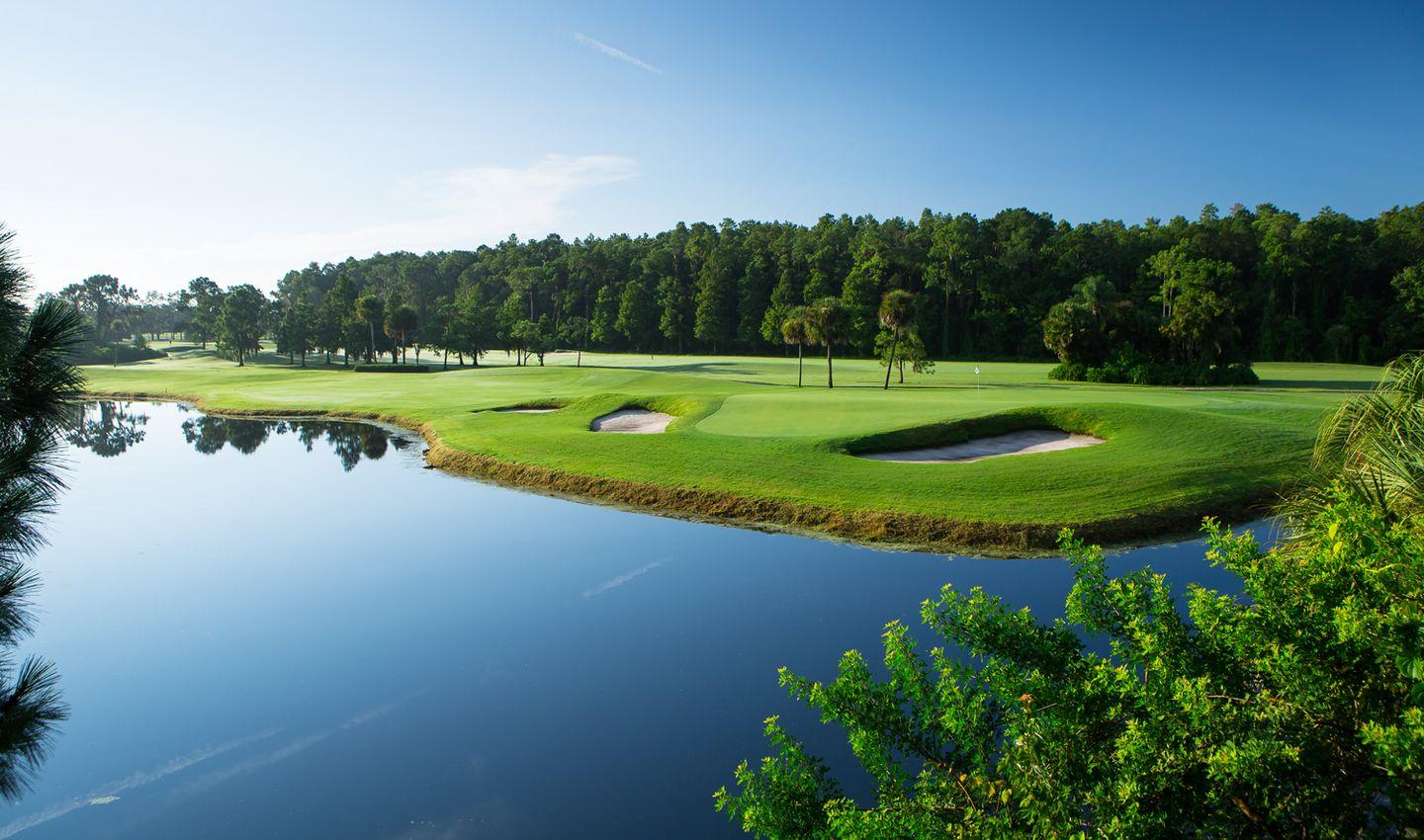 Smooth green sandwiched between a long straight fairway and river that runs through the course