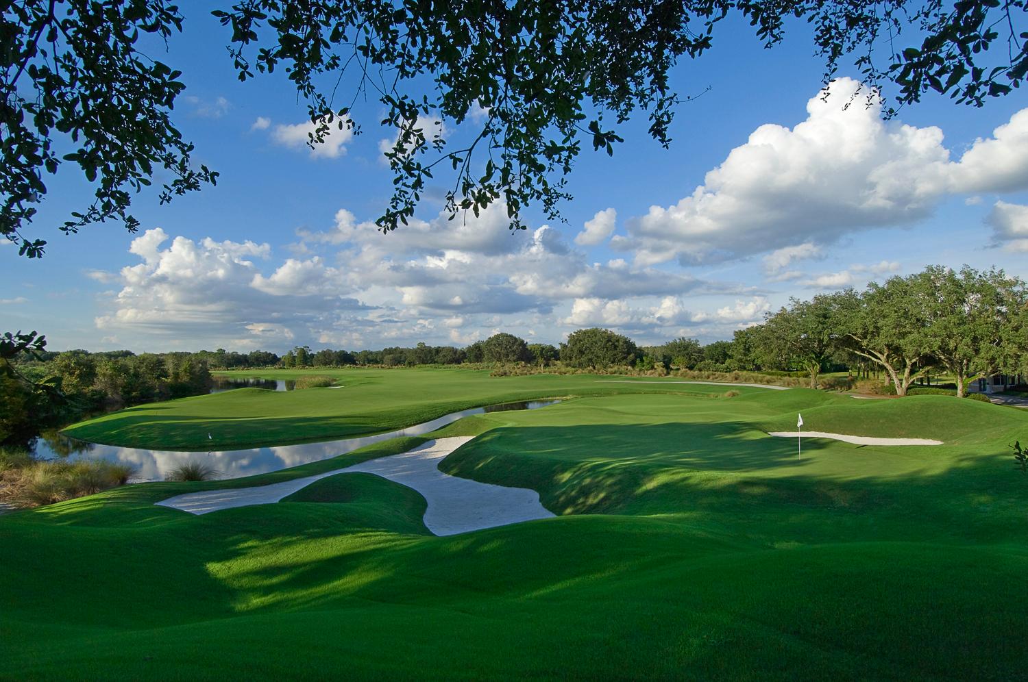 Uniquely shaped sand bunkers placed next to a green with a river that runs through the course