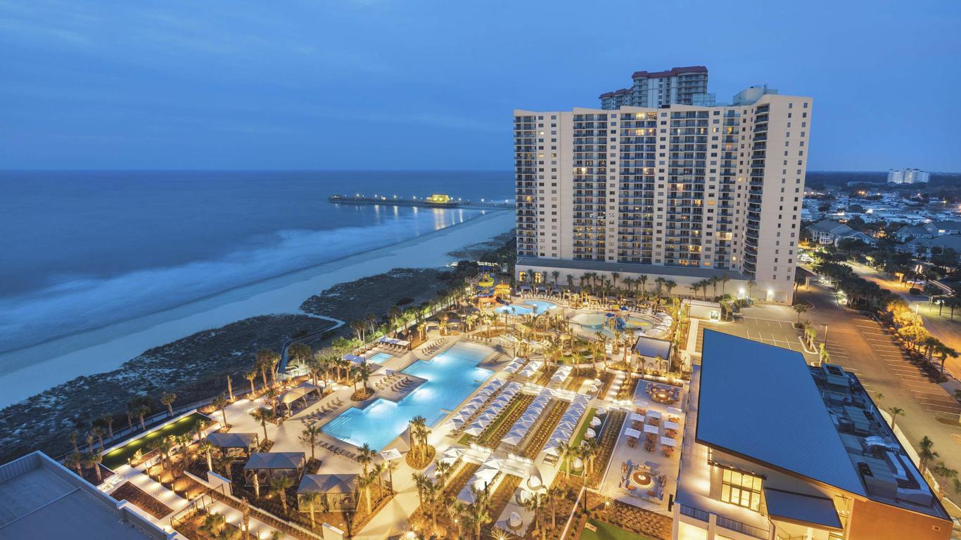 Overhead view of the resort building and outdoor swimming pool being lit up at night