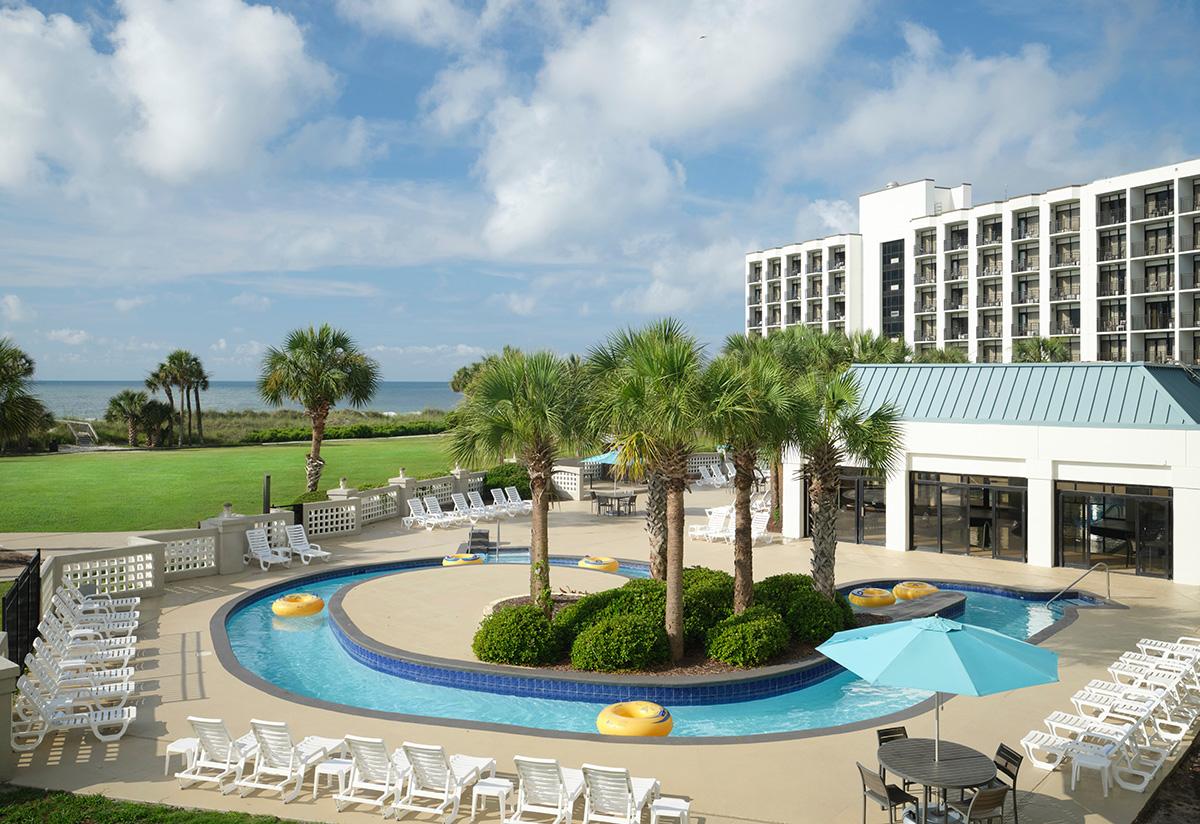 Winding outdoor swimming pool surrounded by sunbeds
