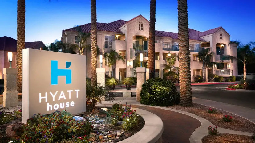 Exterior view of the grand entrance to the Hyatt House hotel with its signed illuminated by blue and white lights