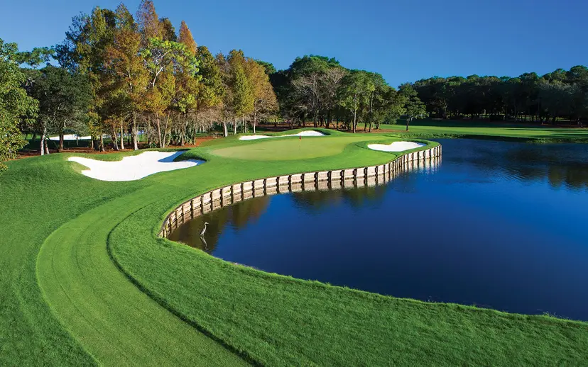 An elevated green nestled with sand bunkers next to a water hazard