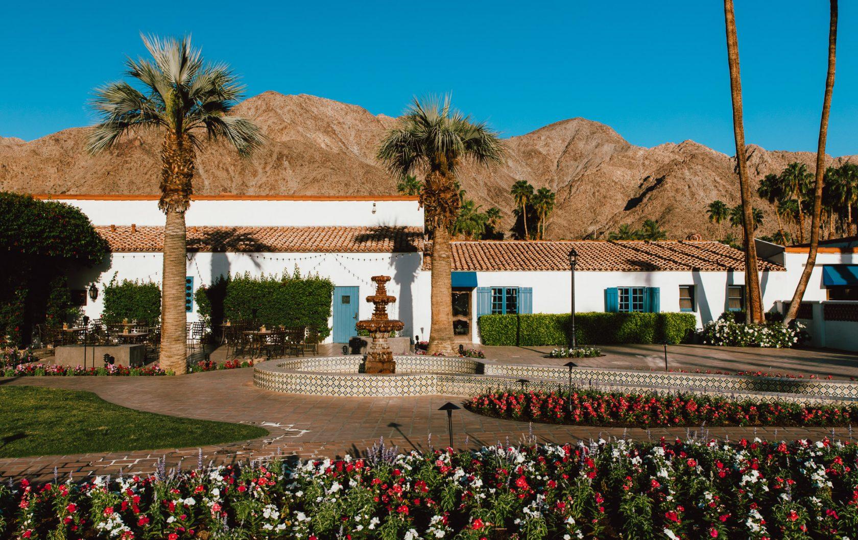 Entrance to the resort featuring palm trees, a water fountain and vibrant flowers to welcome guests