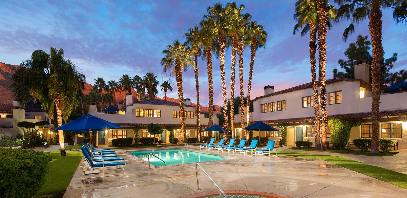 Outdoor swimming pool at the resort with sunbeds alongside palmtrees