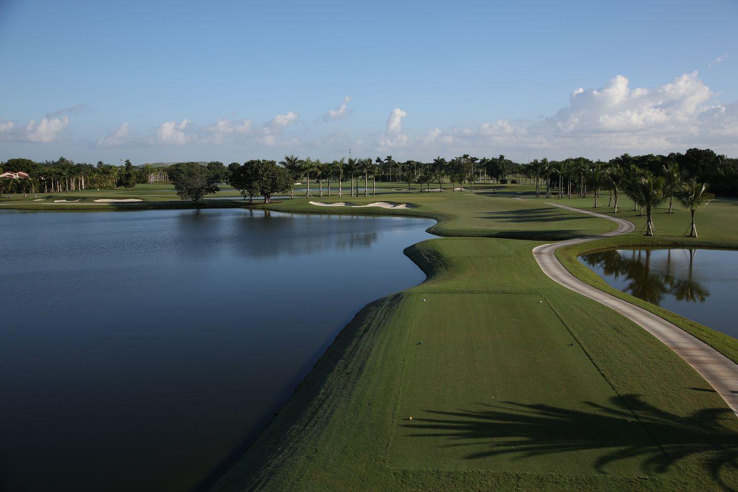 A peaceful golf course landscape with meandering paths and large water features reflecting the sky.