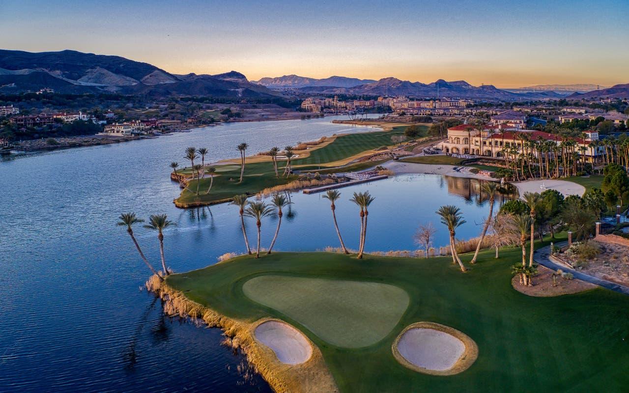 Aerial view of a world-class golf course with smooth greens and serene waterfront scenery.