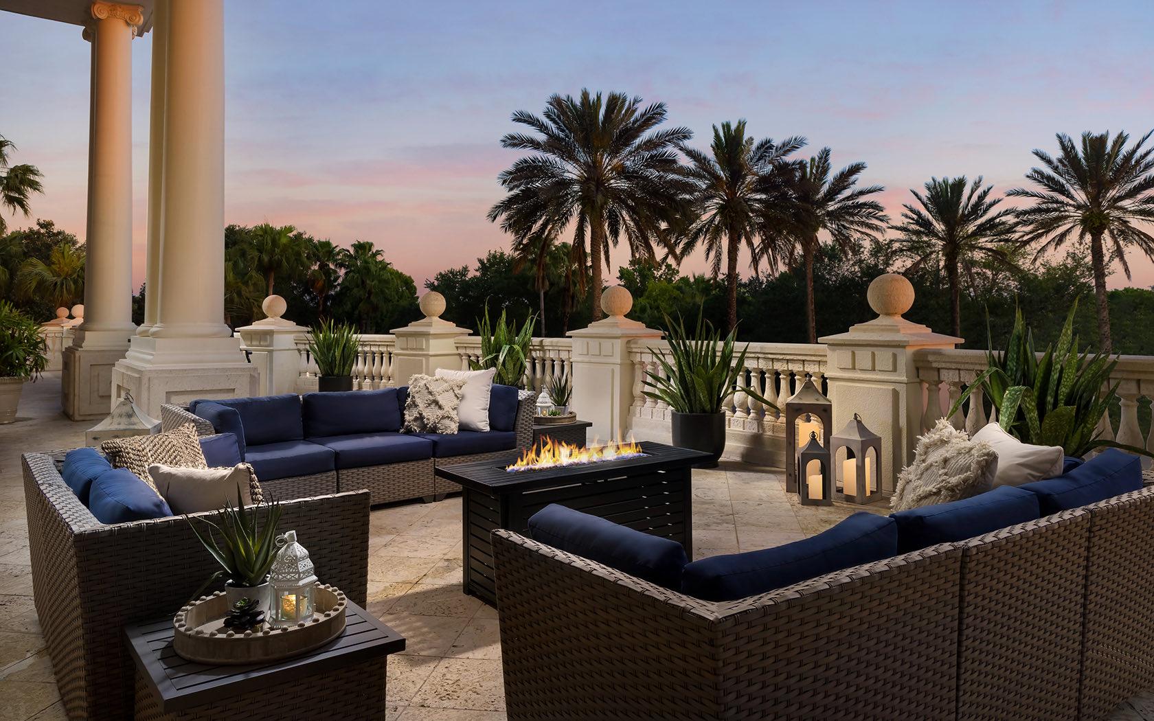 Outdoor eating area featuring a fire pit in the centre with lovely palm trees