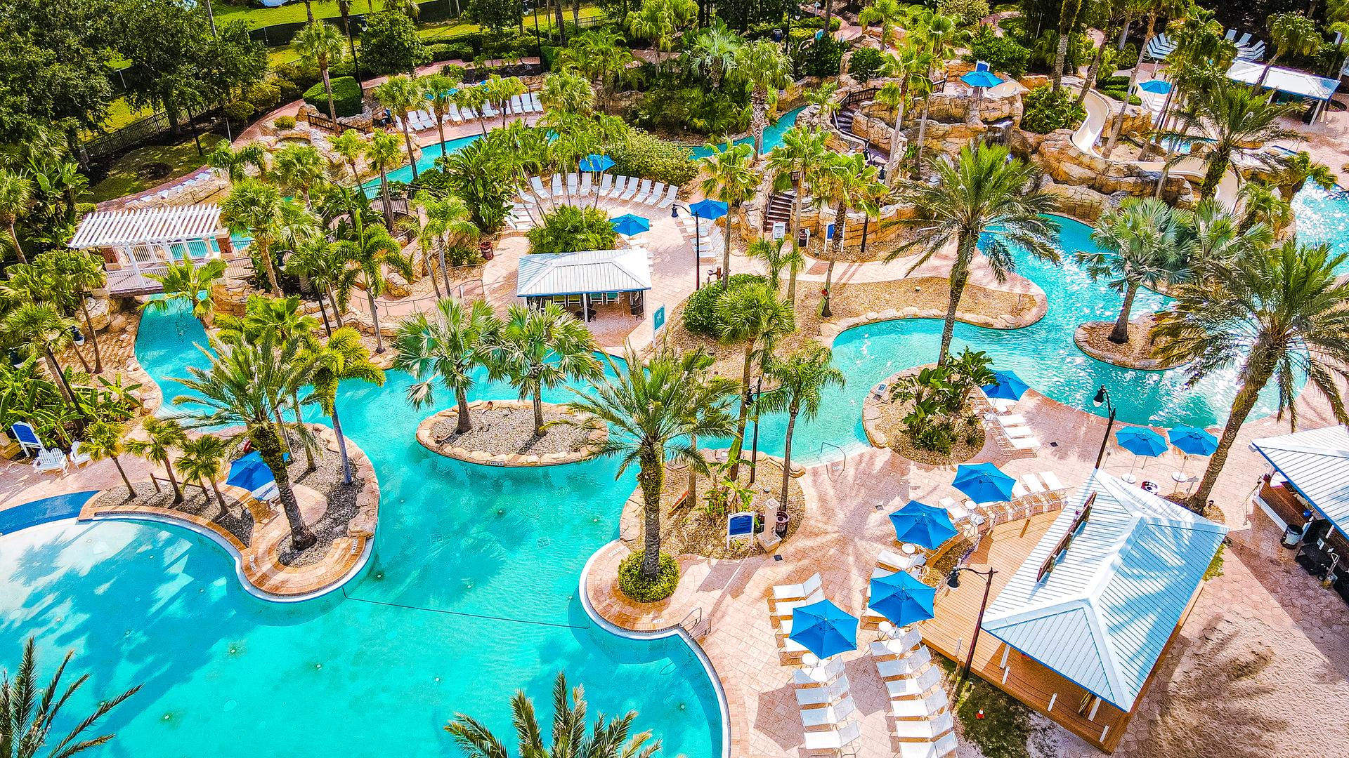 Birdseye view of another outdoor swimming pool which follows a lazy river design and many sunbeds