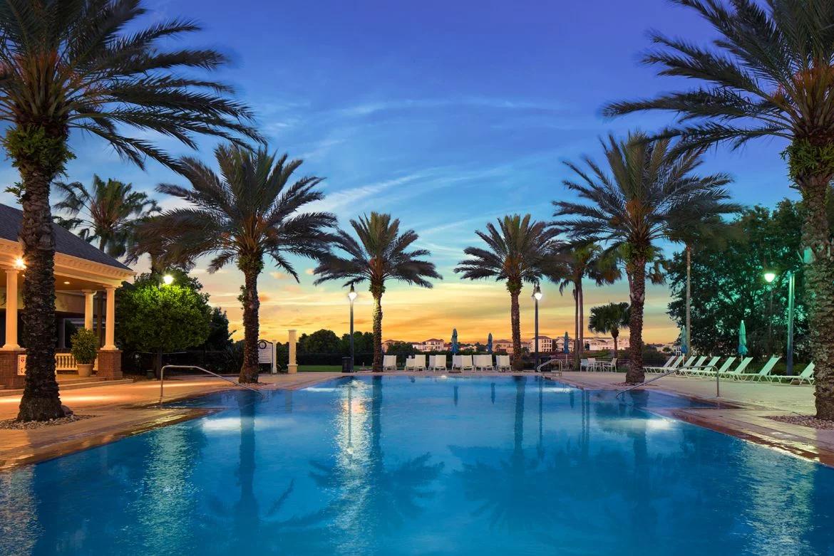 Swimming pool at the Reunion Resort at sun set with the palm trees surrounding reflecting off the water