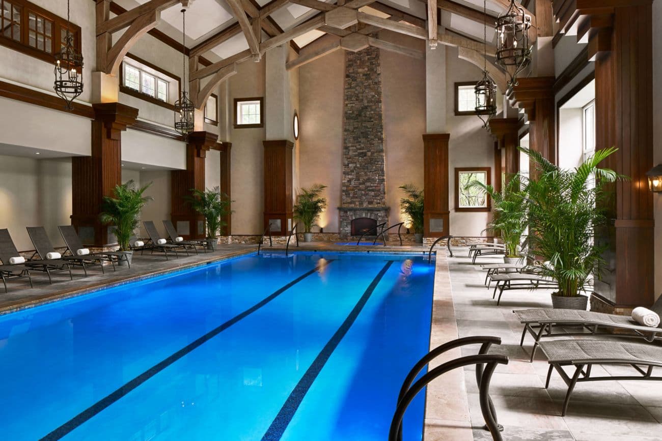 Indoor swimming pool at the hotel with a grand stone and wood design surrounded by sunbeds