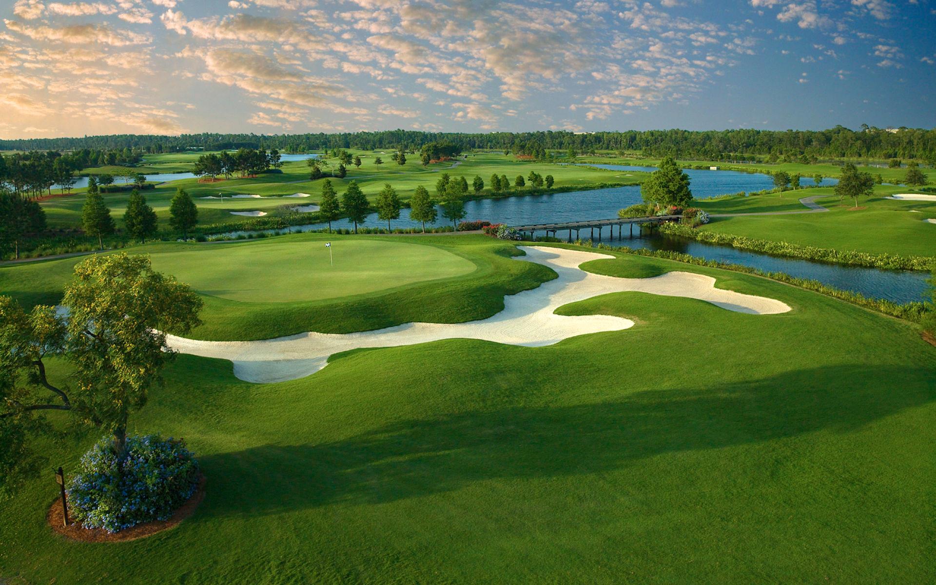 A stunning golf green bordered by water and uniquely shaped white bunkers.