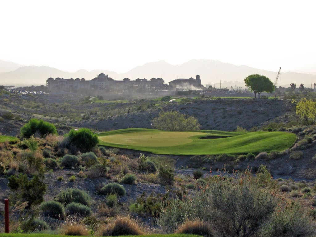 A bushy rough surrounding a well maintained island like green at the TPC Las Vegas course