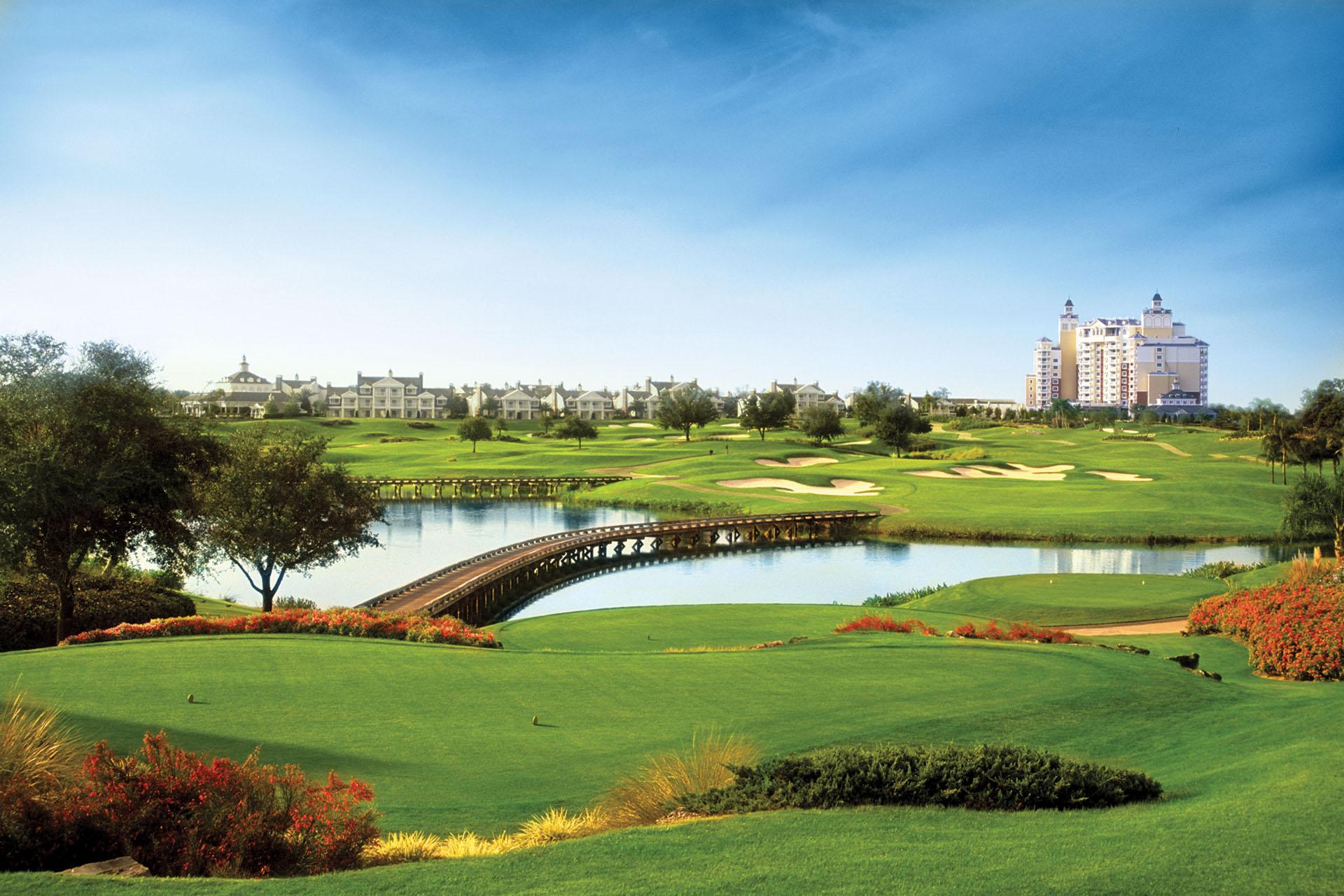 Panoramic view of The Palmer course with a bridge to navigate the water hazard and villas in the distance