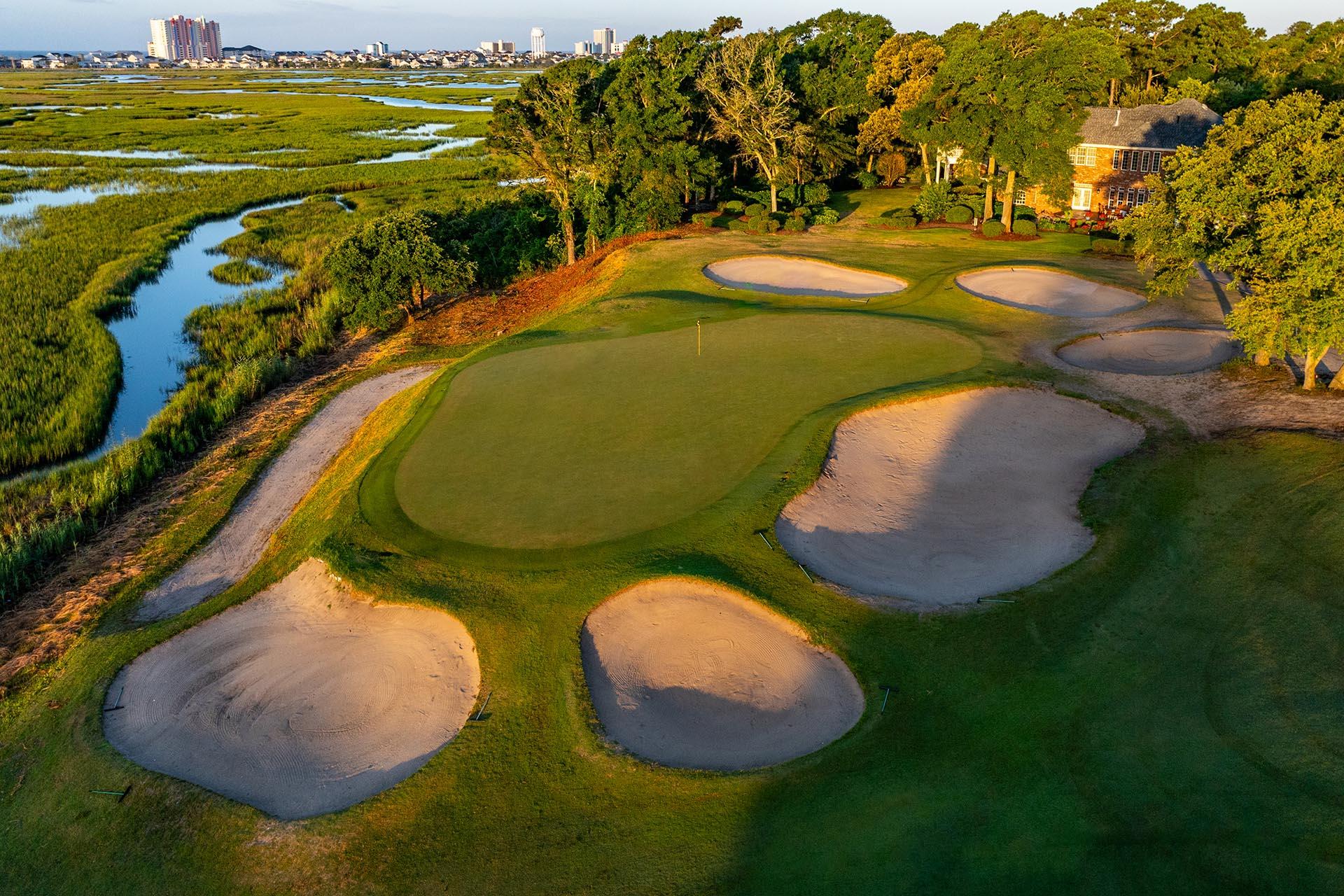 Birdeye view of a smooth green surrounded by sand bunkers