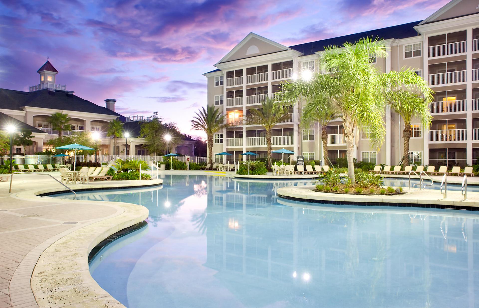 Swimming pool at the hotel designed with palm trees on a calm evening