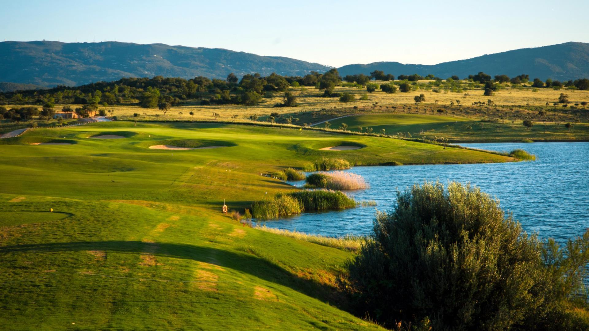 View from a tee box towards on undulating green and a water hazard on the right