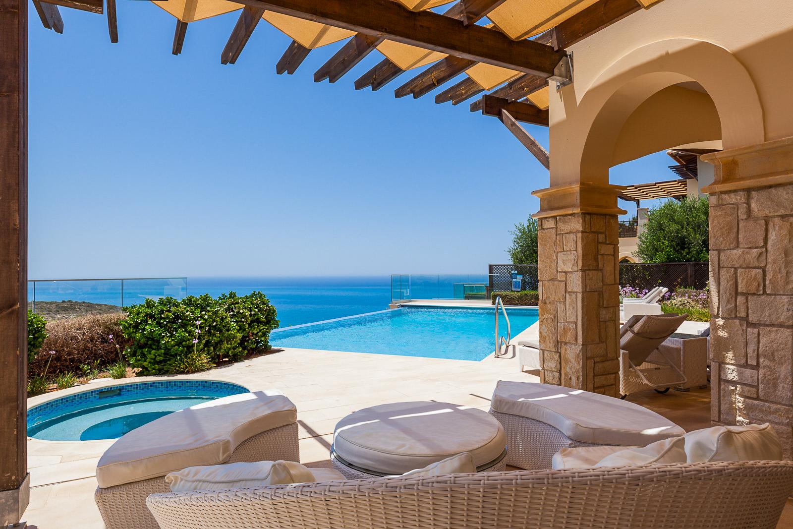Poolside seating area with a jacuzzi and sea views at the Aphrodite Hills Rentals resort